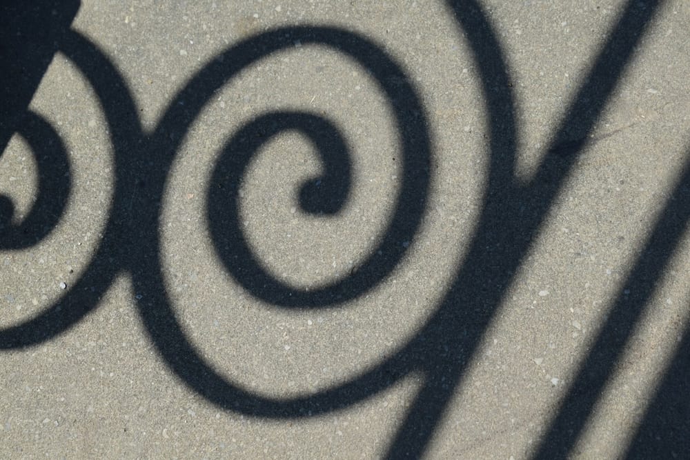 A photo of a shadow on the ground featuring spirals and straight lines