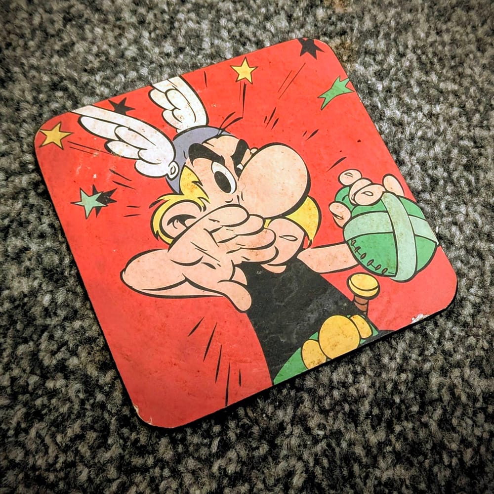 A coaster showing Asterix wiping his mouth and ready for action