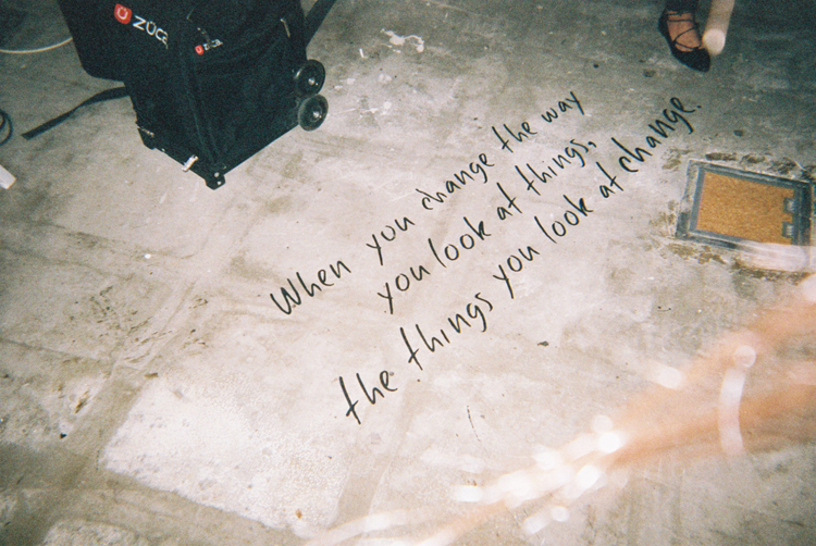 Concrete floor with handwritten quote and a black case in the corner.

"When you change the way you look at things, the things you look at change."