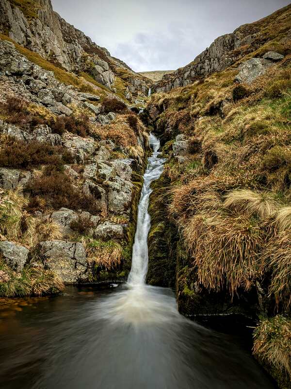 Narrow waterfall in valley captured in long exposure