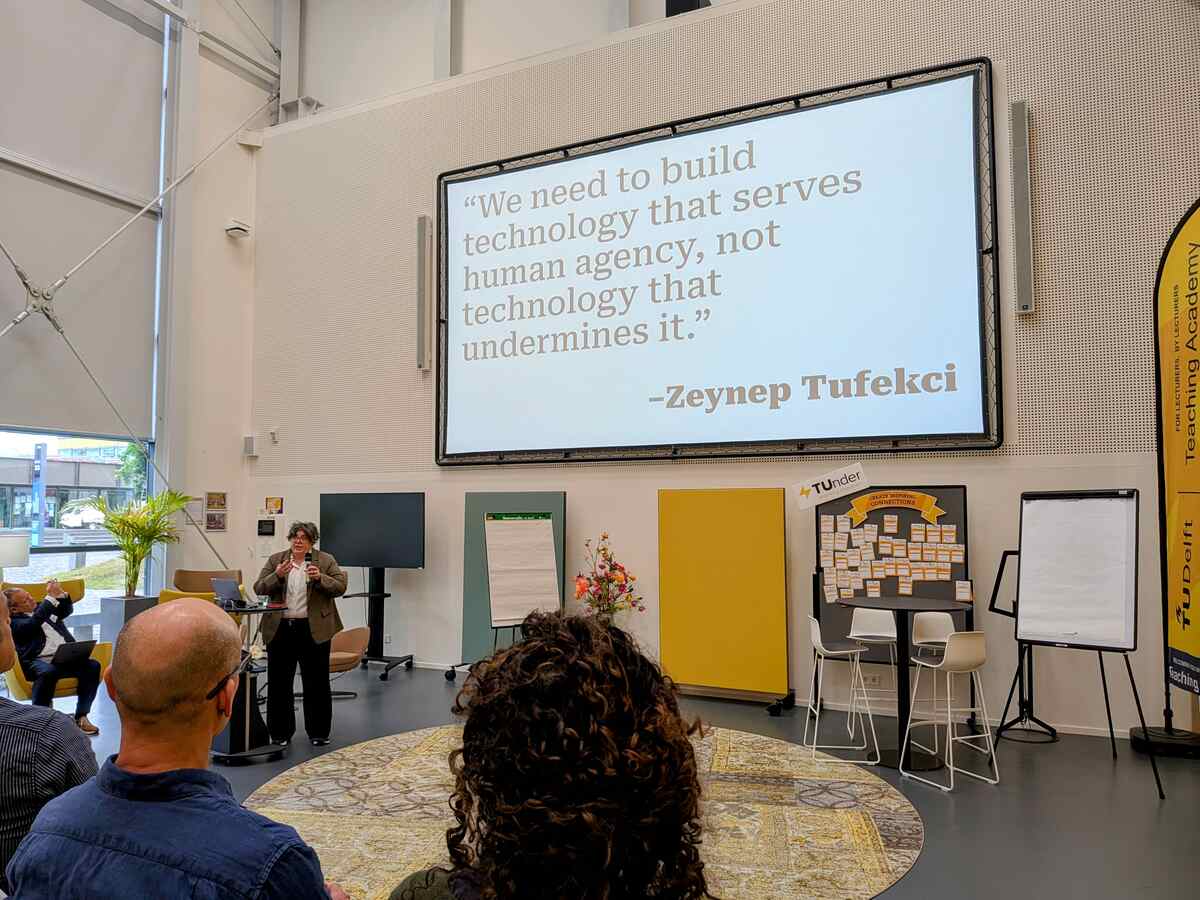 Kerri Lemoie presenting at the DCC Summit. There is a large quotation on the screen behind er from Zeynep Tufekci saying "We need to build technology that serves human agency, not technology that undermines it."