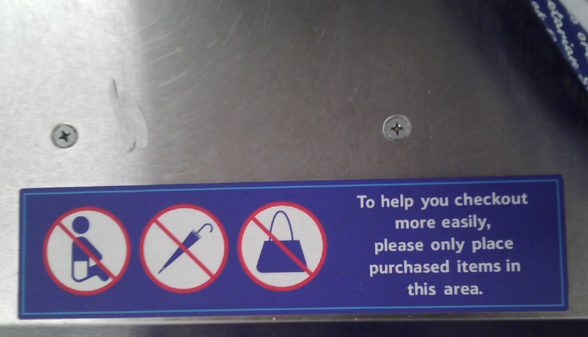 Label on a supermarket self-checkout saying "To help you checkout more easily, please only place purchased items in this area."